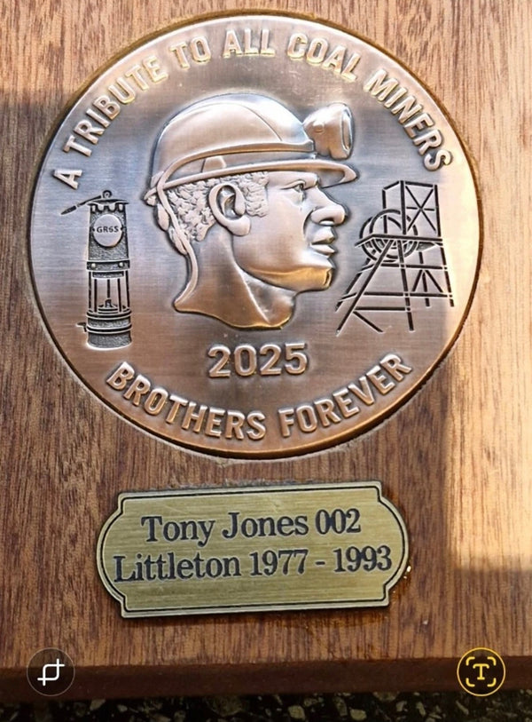 A commemorative plaque honoring coal miners, featuring a detailed miner’s profile and mining symbols with the inscription “A Tribute to All Coal Miners – Brothers Forever 2025.” Mounted on a mahogany base.