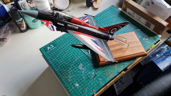 A detailed scale model of a RAF jet aircraft mounted on clear supports above a wooden mahogany base. This display makes it an eye-catching piece for aviation or model enthusiasts. ✈️