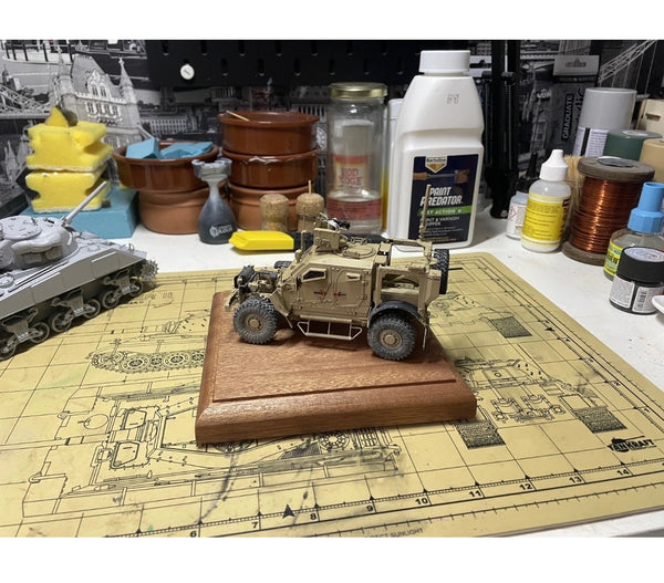 A detailed scale model of a military armored vehicle mounted on a polished mahogany display base. The realistic weathering and fine details make it a striking piece for collectors or model enthusiasts.