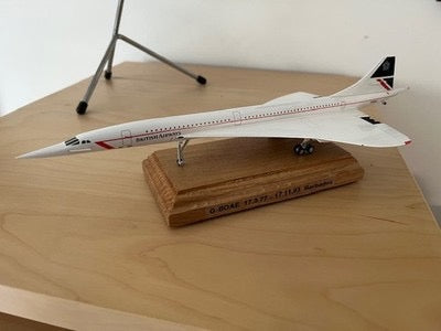 A detailed model of the iconic Concorde supersonic airliner displayed on a polished mahogany  base. A striking tribute to aviation history and the elegance of supersonic travel. ✈️